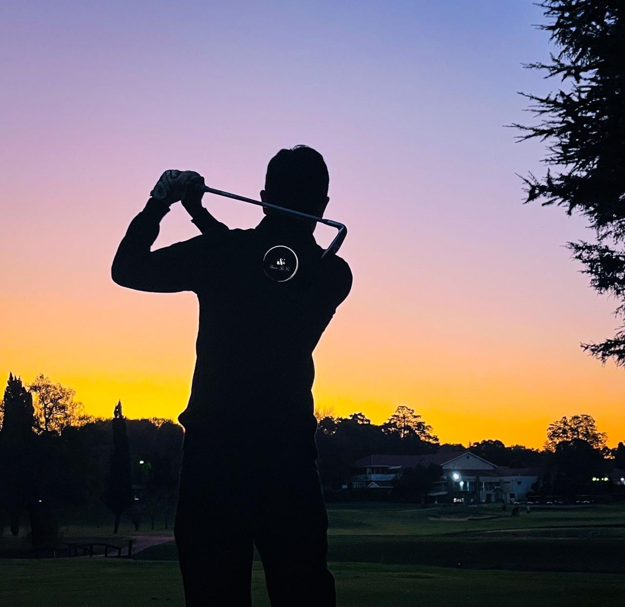 Golfer finishing a swing at sunset